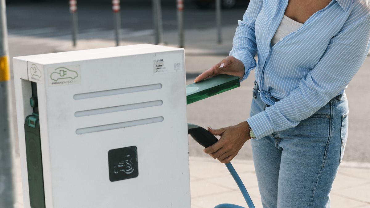 A person charging an electric car at a street charging station — new rules make home EV charging easier for the driveway-less