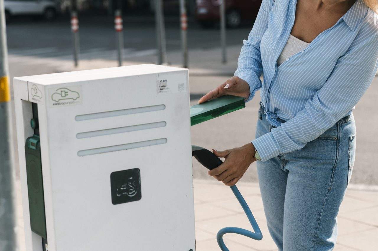 A person charging an electric car at a street charging station — new rules make home EV charging easier for the driveway-less